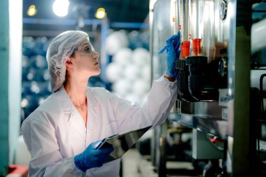 Endüstriyel fabrikadaki ters osmoz makinesinin kalitesini kontrol eden bilim adamı. Geri dönüşümlü taşınabilir fabrika için ölçü basıncıyla kontrol panelinde veri kaydeden kadın işçi.