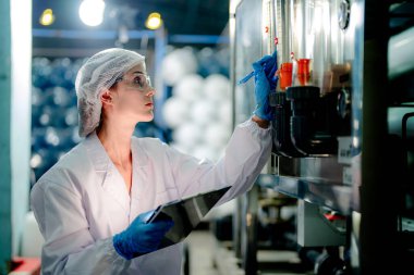 Endüstriyel fabrikadaki ters osmoz makinesinin kalitesini kontrol eden bilim adamı. Geri dönüşümlü taşınabilir fabrika için ölçü basıncıyla kontrol panelinde veri kaydeden kadın işçi.