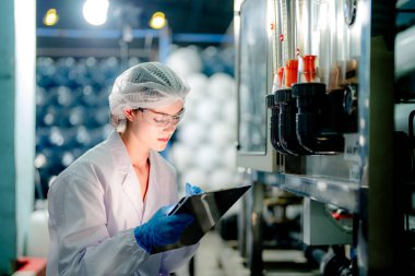 Endüstriyel fabrikadaki ters osmoz makinesinin kalitesini kontrol eden bilim adamı. Geri dönüşümlü taşınabilir fabrika için ölçü basıncıyla kontrol panelinde veri kaydeden kadın işçi.