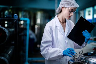 Fabrika işçisi endüstriyel fabrikadaki depoda su şişelerini kontrol ediyor. İçki üretim hattında veri kaydeden kadın işçi..