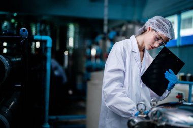 Fabrika işçisi endüstriyel fabrikadaki depoda su şişelerini kontrol ediyor. İçki üretim hattında veri kaydeden kadın işçi..