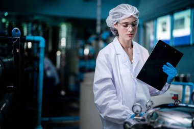 Fabrika işçisi endüstriyel fabrikadaki depoda su şişelerini kontrol ediyor. İçki üretim hattında veri kaydeden kadın işçi..