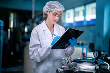 Fabrika işçisi endüstriyel fabrikadaki depoda su şişelerini kontrol ediyor. İçki üretim hattında veri kaydeden kadın işçi..