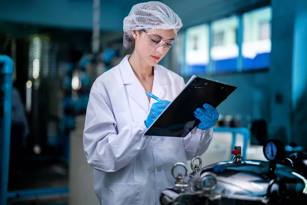 Fabrika işçisi endüstriyel fabrikadaki depoda su şişelerini kontrol ediyor. İçki üretim hattında veri kaydeden kadın işçi..