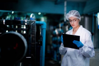 Fabrika çalışanı endüstriyel fabrikadaki depoda su şişelerini kontrol ediyor. İçki üretim hattında veri kaydeden kadın işçi..