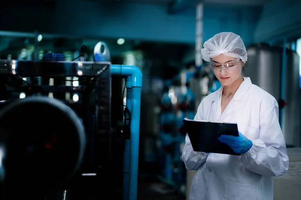 Stock image Factory woman worker checking water bottles in the warehouse at the industrial factory. Female worker recording data at the beverages manufacturing line production.