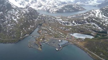Nusfjord otantik balıkçı köyünün kışın gün batımında geleneksel kırmızı rorbu evleri ile en iyi hava manzarası. Lofoten adaları. Norveç. Dağ ve mavi deniz suyunun manzarasının en üst görüntüsü.