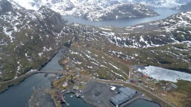 Nusfjord otantik balıkçı köyünün kışın gün batımında geleneksel kırmızı rorbu evleri ile en iyi hava manzarası. Lofoten adaları. Norveç. Dağ ve mavi deniz suyunun manzarasının en üst görüntüsü.