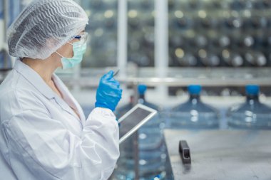 Kadın fabrika işçileri endüstriyel fabrikadaki makine sistemlerini kontrol ediyorlar. Kadınlar içecek ve gıda üretimi için temiz odalarda çalışıyorlar