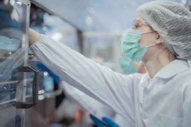 Kadın fabrika işçileri endüstriyel fabrikadaki makine sistemlerini kontrol ediyorlar. Kadınlar içecek ve gıda üretimi için temiz odalarda çalışıyorlar