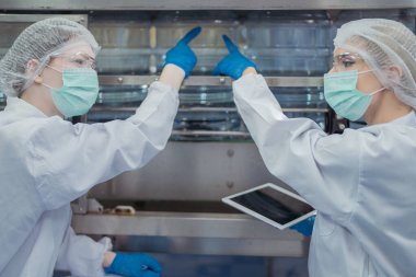 Bilim adamı, endüstriyel fabrikanın makine taşıma hattındaki su şişelerinin kalitesini kontrol ediyor. İçki üretim hattında veri kaydeden kadın işçi..