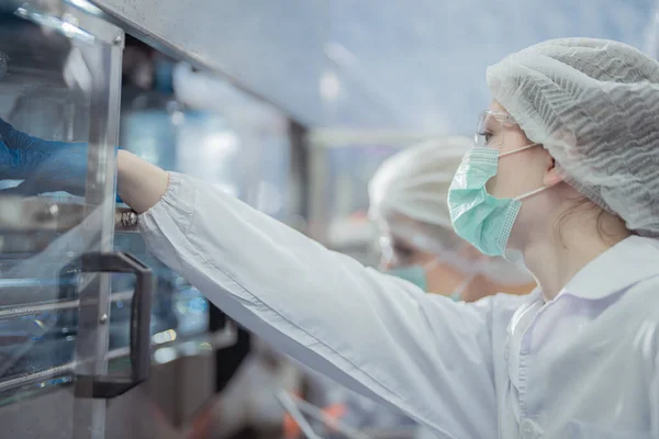 在工厂的机器输送机上 科学家正在检查水瓶的质量 饮料生产线的女工记录数据 — 图库照片