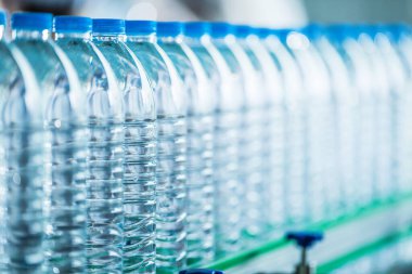 İçecek fabrikasında bir sürü maden suyu şişesi var. Üretim hattındaki temiz plastik içme suyu şişeleri..