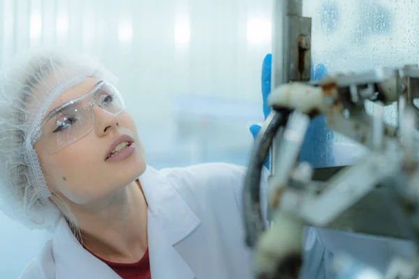 機械の水ディスペンサーを点検する工場女性エンジニア 労働者は産業工場の機械コンベヤー ラインの水びんの質を点検します — ストック写真