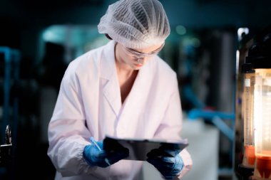 Endüstriyel fabrikadaki ters osmoz makinesinin kalitesini kontrol eden bilim adamı. Geri dönüşümlü taşınabilir fabrika için ölçü basıncıyla kontrol panelinde veri kaydeden kadın işçi.