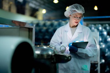 Endüstriyel fabrikadaki ters osmoz makinesinin kalitesini kontrol eden bilim adamı. Geri dönüşümlü taşınabilir fabrika için ölçü basıncıyla kontrol panelinde veri kaydeden kadın işçi.