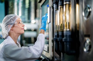 Endüstriyel fabrikadaki makine sistemindeki kontrol panelini kontrol eden kadın bilim kadını. Kontrol panelinde su seviyesi basıncıyla veri kaydeden kadın işçi.