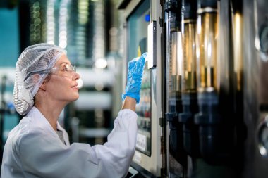 Endüstriyel fabrikadaki makine sistemindeki kontrol panelini kontrol eden kadın bilim kadını. Kontrol panelinde su seviyesi basıncıyla veri kaydeden kadın işçi.