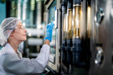 Endüstriyel fabrikadaki makine sistemindeki kontrol panelini kontrol eden kadın bilim kadını. Kontrol panelinde su seviyesi basıncıyla veri kaydeden kadın işçi.