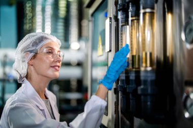 Endüstriyel fabrikadaki makine sistemindeki kontrol panelini kontrol eden kadın bilim kadını. Kontrol panelinde su seviyesi basıncıyla veri kaydeden kadın işçi.