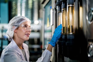 Endüstriyel fabrikadaki makine sistemindeki kontrol panelini kontrol eden kadın bilim kadını. Kontrol panelinde su seviyesi basıncıyla veri kaydeden kadın işçi.