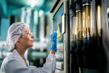 Endüstriyel fabrikadaki makine sistemindeki kontrol panelini kontrol eden kadın bilim kadını. Kontrol panelinde su seviyesi basıncıyla veri kaydeden kadın işçi.