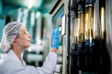 Endüstriyel fabrikadaki makine sistemindeki kontrol panelini kontrol eden kadın bilim kadını. Kontrol panelinde su seviyesi basıncıyla veri kaydeden kadın işçi.