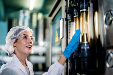 Endüstriyel fabrikadaki makine sistemindeki kontrol panelini kontrol eden kadın bilim kadını. Kontrol panelinde su seviyesi basıncıyla veri kaydeden kadın işçi.