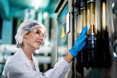 Endüstriyel fabrikadaki makine sistemindeki kontrol panelini kontrol eden kadın bilim kadını. Kontrol panelinde su seviyesi basıncıyla veri kaydeden kadın işçi.