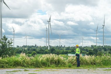 Dışarıda saha çalışması yapan bir mühendis. Rüzgâr türbini teknisyenleri rüzgar enerjisini elektrik enerjisine dönüştüren rüzgar türbinlerinin elektrik jeneratörlerini kontrol ediyor.