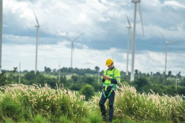 Dışarıda saha çalışması yapan bir mühendis. Rüzgâr türbini teknisyenleri rüzgar enerjisini elektrik enerjisine dönüştüren rüzgar türbinlerinin elektrik jeneratörlerini kontrol ediyor.