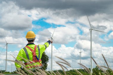 Dışarıda saha çalışması yapan bir mühendis. Rüzgâr türbini teknisyenleri rüzgar enerjisini elektrik enerjisine dönüştüren rüzgar türbinlerinin elektrik jeneratörlerini kontrol ediyor.