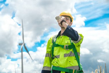 İşçi içme suyu. Rüzgâr türbini teknisyenleri rüzgar enerjisini elektrik enerjisine dönüştüren rüzgar türbinlerinin elektrik jeneratörlerini kontrol ediyor.