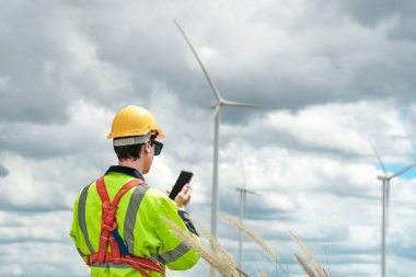 Dışarıda saha çalışması yapan bir mühendis. Rüzgâr türbini teknisyenleri rüzgar enerjisini elektrik enerjisine dönüştüren rüzgar türbinlerinin elektrik jeneratörlerini kontrol ediyor.