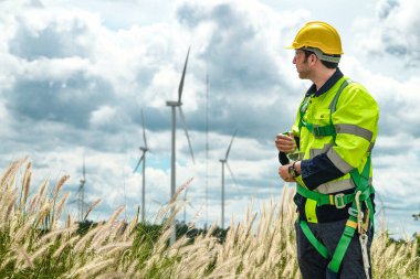 Dışarıda saha çalışması yapan bir mühendis. Rüzgâr türbini teknisyenleri rüzgar enerjisini elektrik enerjisine dönüştüren rüzgar türbinlerinin elektrik jeneratörlerini kontrol ediyor.