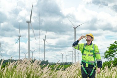 Dışarıda saha çalışması yapan bir mühendis. Rüzgâr türbini teknisyenleri rüzgar enerjisini elektrik enerjisine dönüştüren rüzgar türbinlerinin elektrik jeneratörlerini kontrol ediyor.