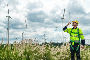 Dışarıda saha çalışması yapan bir mühendis. Rüzgâr türbini teknisyenleri rüzgar enerjisini elektrik enerjisine dönüştüren rüzgar türbinlerinin elektrik jeneratörlerini kontrol ediyor.