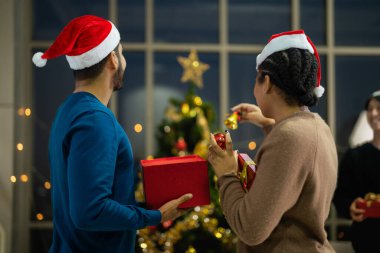 Güzel Asyalı çift kadın ve erkek kutluyor. Mutlu aşıklar Noel arifesinde kutlamayı kutlar, kutuyu açar ve birlikte oturma odasında sunarlar..