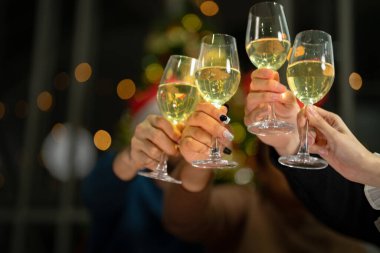 Işıklı şampanya bardaklarını kapatın. Şampanya içilen bir akşam yemeği. Eller temiz bardağı alkolle sarıda tutarken yansıtır..