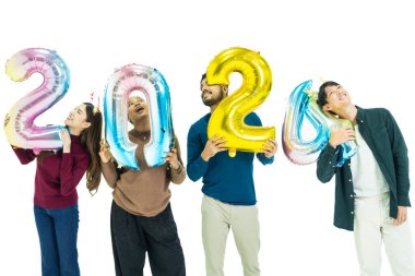 Bir grup insan yeni yıl için 2024 sayısının fantezi renkli balonlarını tutuyor. Beyaz arka planda duran kadın ve erkekler. Mutlu yıllar partisi.