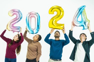 Bir grup insan yeni yıl için 2024 sayısının fantezi renkli balonlarını tutuyor. Beyaz arka planda duran kadın ve erkekler. Mutlu yıllar partisi.