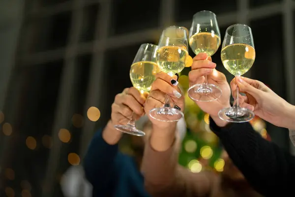 close up glasses of clinking glasses of champagne with lighting. Dinner party with drinking of champagne. hands holding clear glass with alcohol in yellow shine reflect.