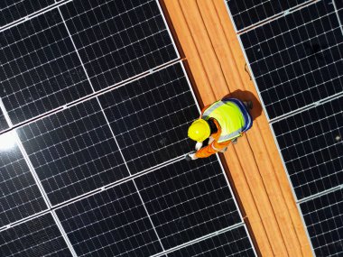 Üst düzey mühendisler çatıdaki güneş pili paneli veya fotovoltaik hücrenin yapımını denetliyor. Yeşil enerjinin endüstriyel yenilenebilir enerjisi. Kentsel alanda bir fabrika. İşçi kule çatısında çalışıyor..