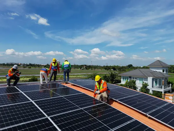 Mühendis çatıdaki güneş pili panelinin veya fotovoltaik hücrenin yapımını denetliyor. Yeşil enerjinin endüstriyel yenilenebilir enerjisi. Kentsel alanda bir fabrika. İşçi kule çatısında çalışıyor..