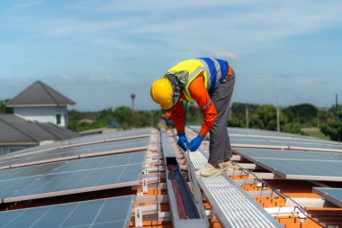 İşçi teknisyenler çatıda güneş panelleri sistemi kurmaya çalışıyorlar. Güneş fotovoltaik panel sistemi kuruluyor. Alternatif enerji ekolojik kavramı. Yenilenebilir temiz enerji teknolojisi kavramı.