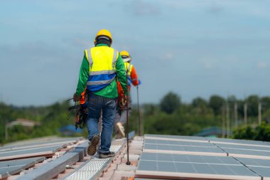 İşçi teknisyenler çatıda güneş panelleri sistemi kurmaya çalışıyorlar. Güneş fotovoltaik panel sistemi kuruluyor. Alternatif enerji ekolojik kavramı. Yenilenebilir temiz enerji teknolojisi kavramı.