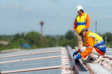 İşçi teknisyenler çatıda güneş panelleri sistemi kurmaya çalışıyorlar. Güneş fotovoltaik panel sistemi kuruluyor. Alternatif enerji ekolojik kavramı. Yenilenebilir temiz enerji teknolojisi kavramı.