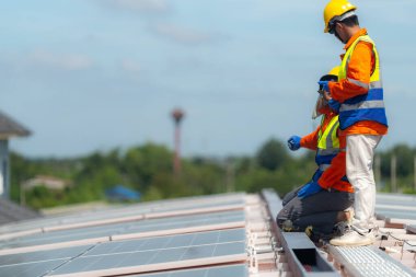 İşçi teknisyenler çatıda güneş panelleri sistemi kurmaya çalışıyorlar. Güneş fotovoltaik panel sistemi kuruluyor. Alternatif enerji ekolojik kavramı. Yenilenebilir temiz enerji teknolojisi kavramı.