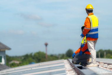 İşçi teknisyenler çatıda güneş panelleri sistemi kurmaya çalışıyorlar. Güneş fotovoltaik panel sistemi kuruluyor. Alternatif enerji ekolojik kavramı. Yenilenebilir temiz enerji teknolojisi kavramı.