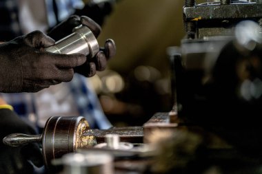 Metal Lathes için el operasyonunu kapatın. Makinede yuvarlanan çelik kolon. Metal endüstrisi. İşçi el tamirci motoru kontrol eder. Teknisyen fabrikadaki metal makinesinde matkap ucu onarıyor.